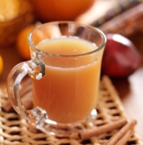 glass of apple cider with fall themed background.